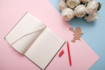 Notebook and bouquet of white roses flowers. Two-tone background, pink and blue paper. Modern love concept. 
