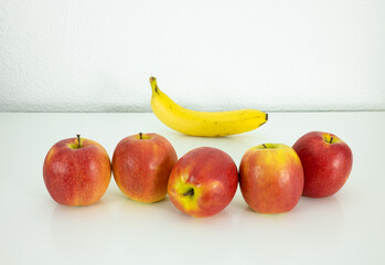 Five ripe apples and banana on the white background