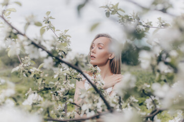 girl in a white dress walks in an apple orchard