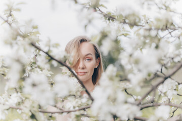 Fototapeta na wymiar girl in a white dress walks in an apple orchard