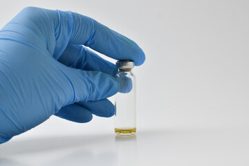 Naklejka premium A blue-gloved hand holds the vials of the vaccine. copies a space. Vaccination.
