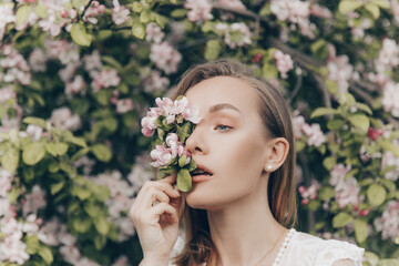 Naklejka premium girl in a white dress walks in an apple orchard