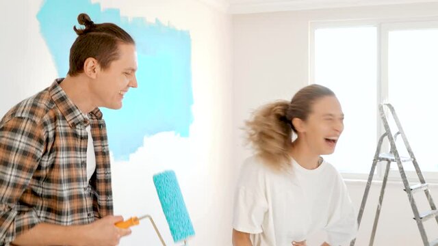 Couple doing renovating at home and singing on paint roller. Renovation in cozy apartment flat, repair and makeover