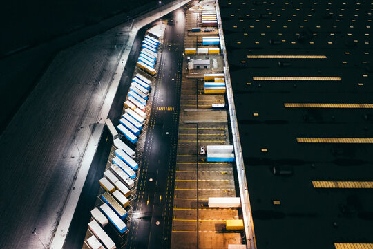 Aerial view of the trucks unloading at the logistic center. Night view with a bit of snow.