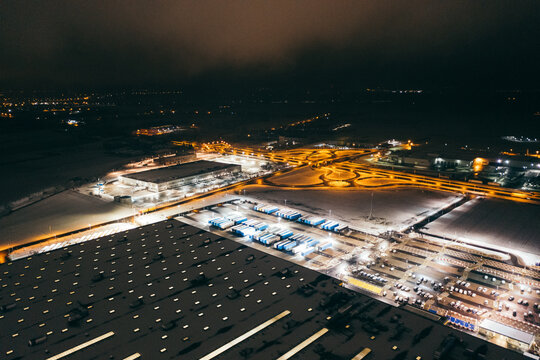 Aerial view of the trucks unloading at the logistic center. Night view with a bit of snow.