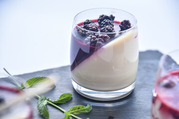 Delicious home made dessert panna cotta with berry sauce, fresh berries and mint in glasses