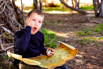 A clever boy searches an ancient map for something buried in a forest.