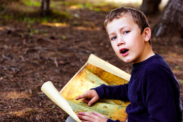 A clever boy searches an ancient map for something buried in a forest.