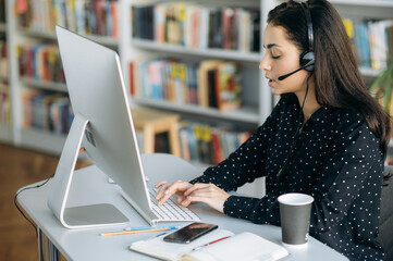 Focused woman have a serious conversation, sitting at the table. Elegant female wearing headset,...