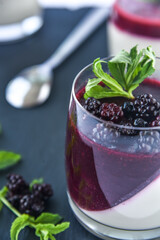 Delicious home made dessert panna cotta with berry sauce, fresh berries and mint in glasses