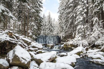 Winter waterfall , a lot of snow by the water, background of winter forest
