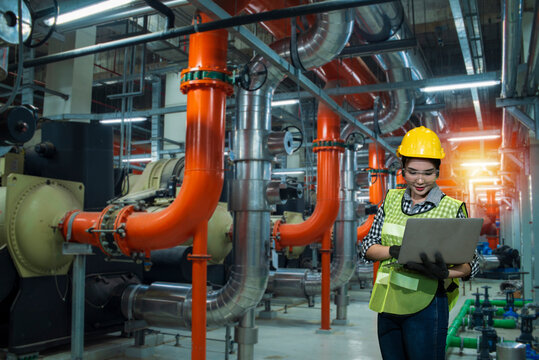 industrial plant in factory, women worker using  laptop on chiller water cool in plant room background.