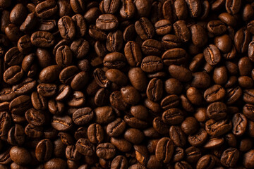 Fresh roasted coffee beans closeup on black stone background. Food pattern. Top view, flat lay with copy space