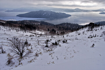 高所から見下ろす曇り空の下の冬の湖。日本の北海道の屈斜路湖。