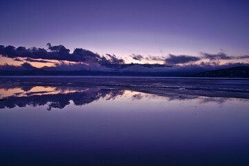 夕暮れの湖の風景。鏡面の湖面に映る黄昏の空と雲。屈斜路湖、北海道、日本。