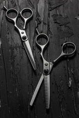 Metallic barber scissors on top of dark background.