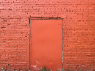 bright red brick barn building wall freshly painted with metal door