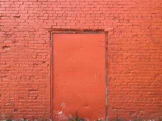 bright red brick barn building wall freshly painted with metal door