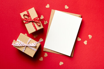 Valentines day card mockup with gift boxes and small hearts on red paper background