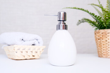 Bathroom background, toilet accessories for hand and body care, liquid soap dispenser and towels against light background