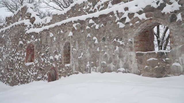 Ruins of Dobele castle in Latvia. The stone walls. Historical building fragments in a panoramic view. The territory landscape design in winter.