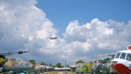Passenger plane flying over the old planes open-air museum. Blue sky with clouds