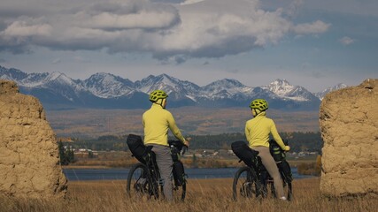 The man and woman travel on mixed terrain cycle bike touring with bikepacking. The two people...