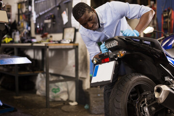 Fototapeta na wymiar Afro american expert inspects the wheel of a motorcycle. High quality photo