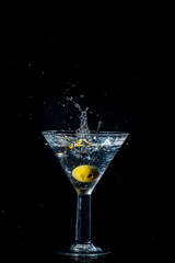Olive dropping and splashing into a martini glass