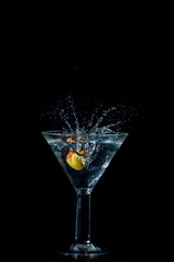 Olive dropping and splashing into a martini glass