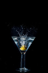 Olive dropping and splashing into a martini glass