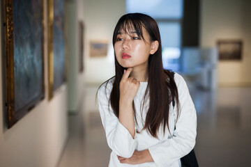 Portrait of chinese young woman near picture collection in the museum