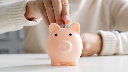 Closeup man hand put coin money to piggy bank, saving and deposit money concept