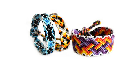 Selective focus of tied woven friendship bracelets with bright colorful patterns handmade of thread isolated on white background