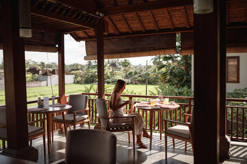 A happy young caucasian woman having a breakfast in a restaurant, drink tea