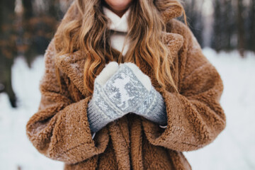 Young woman in fur coat, gloves and scarf in snowy forest
