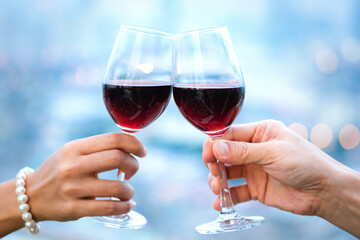 Hand of a lover's dinner is celebrated with red wine at a restaurant in a romantic atmosphere. Sunset and modern city background