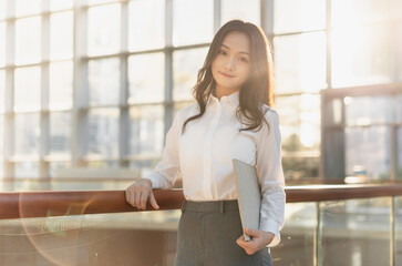 Fototapeta premium Asian business people holding a laptop leaning against the railing