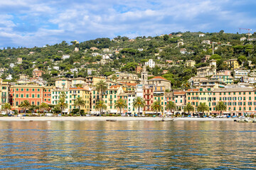 Italy. A picturesque town on the Ligurian coast. Colorful colorful Mediterranean houses on the coastline of a stone beach among green trees. A popular resort and tourist destination.