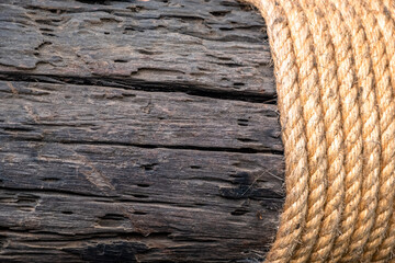 Rope on wood. Cream colored manila rope wrapped around old hardwood plank with rough surface.
