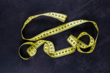  meter yellow tape for sewing and needlework lies on the black surface