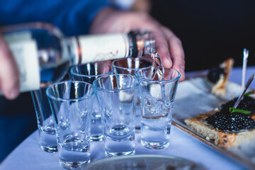 View of alcohol setting on catering banquet table, row line of ice cold vodka shots decorated catering bouquet table event