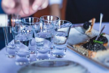View of alcohol setting on catering banquet table, row line of ice cold vodka shots decorated catering bouquet table event
