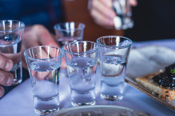 View of alcohol setting on catering banquet table, row line of ice cold vodka shots decorated catering bouquet table event