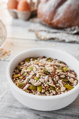 vertical raw different types of seeds in a small round white porcelain cup. well-being philosophy in food, balanced nutrition food, selective focus