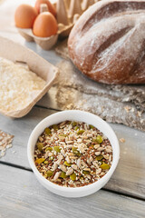 raw different grains and seeds in small plate on background of cooking homemade dishes. wellness food at home, vertical food content, selective focus