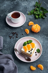 Sponge cake layers with buttercream, decorated with slices of tangerine chocolate and mint. Delicious sweet dessert for tea.