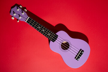 Fototapeta na wymiar Four string ukulele guitar on red background