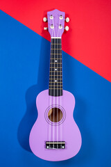 Four string ukulele guitar on blue-red background