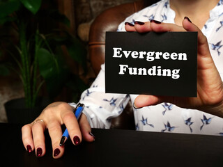 Financial concept meaning Evergreen Funding with sign on blank card in hand.